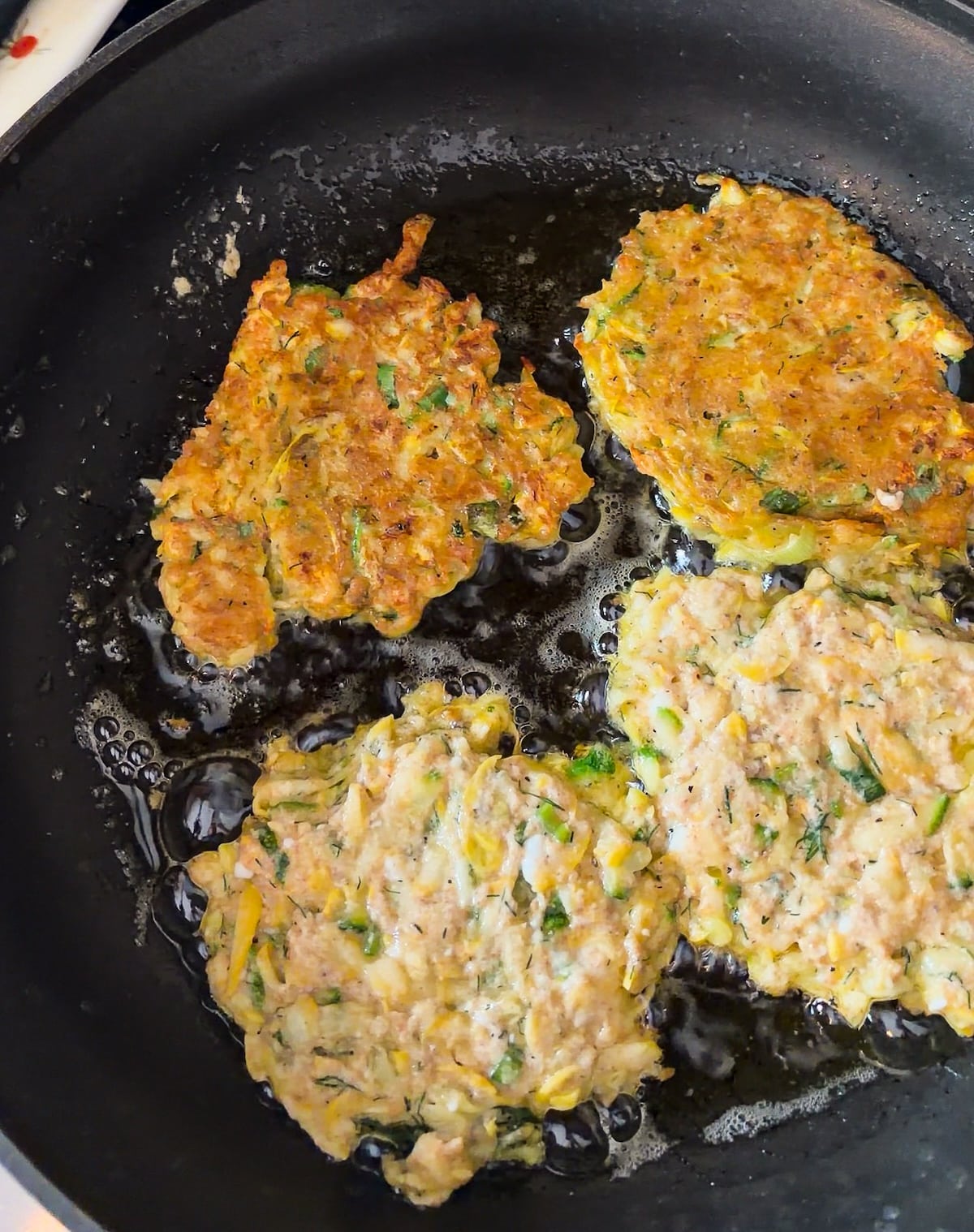 frying-fritters.jpg Frying zucchini fritters in a skillet with oil.
