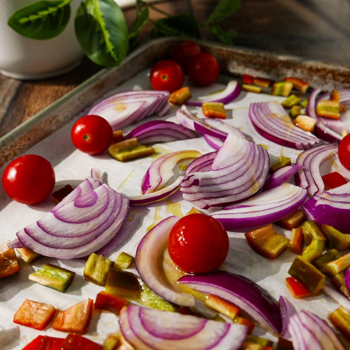 tomatoes-onion-and-pepper.jpg Bell pepper, red onion, and cherry tomatoes on a baking sheet.
