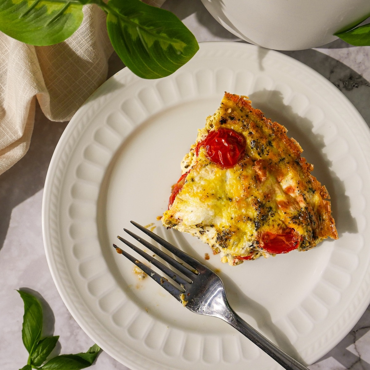 zucchini-frittata.jpg Slice of zucchini frittata with eggplant and tomatoes.